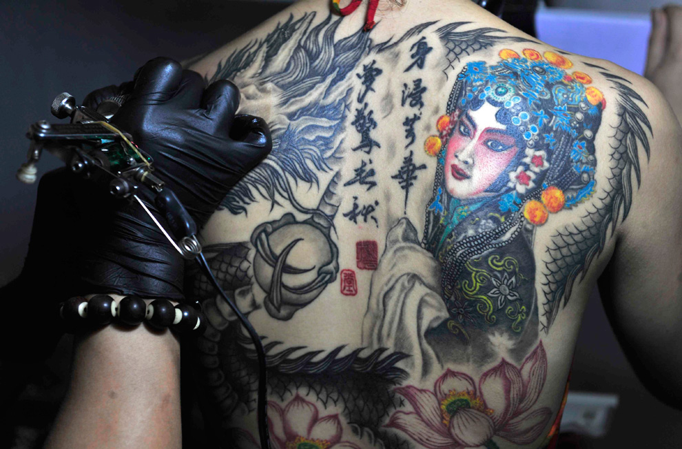 An artist works on a customer at the National Tattoo Competition in Shenyang