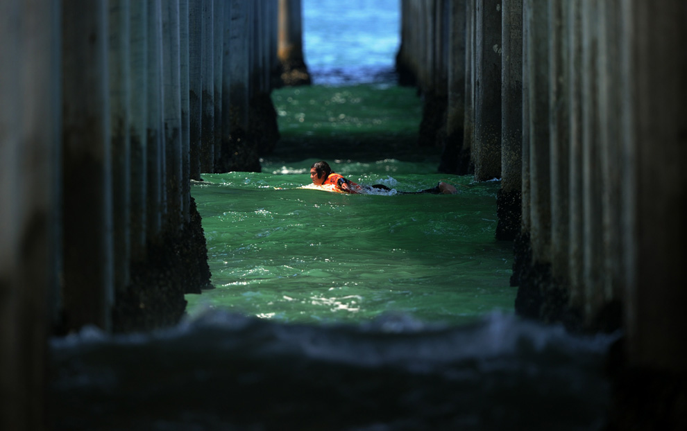 Surfer Kekoa Bacalso paddles through the pier as he competes in his heat during the US Open of Surfing at Huntington Beach, California on August 4, 2010. (MARK RALSTON/AFP)