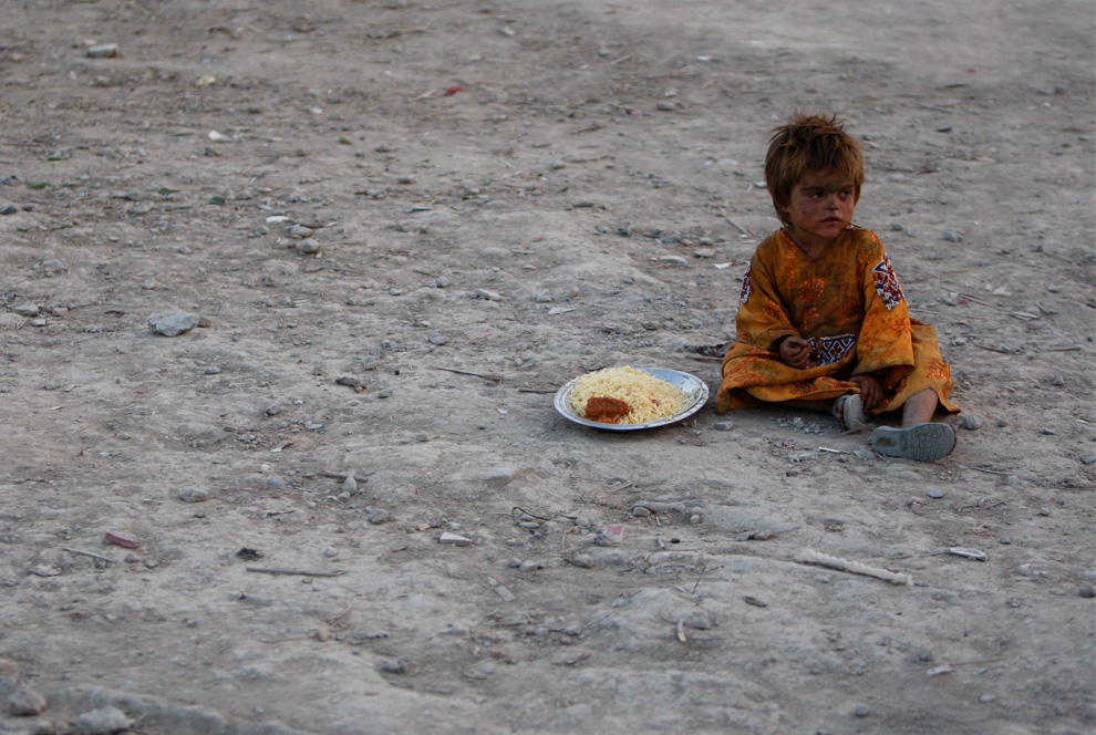 A child sits with a plate of food that was distributed as part of the holy month of Ramadan, at a refugee camp in Kabul, Afghanistan, on Saturday, Aug. 14, 2010. (AP Photo/Mustafa Quraishi)