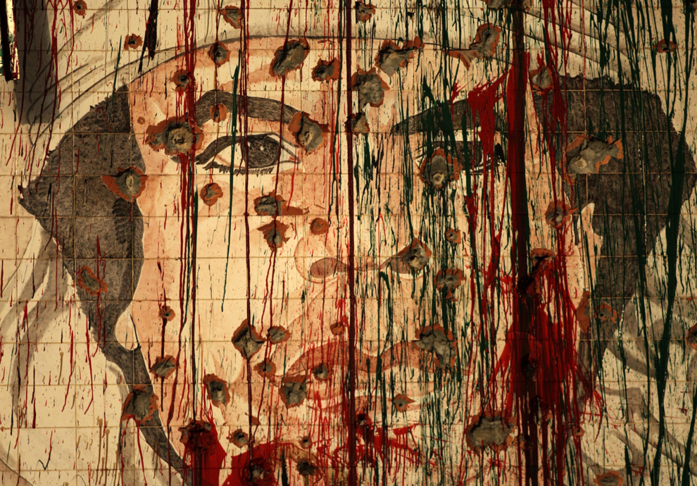 A defaced portrait of fugitive Libyan leader Moamer Kadhafi in Tripoli on Sept. 1, 2011 as the fallen strongman vowed again not to surrender in a message broadcast on the 42nd anniversary of the coup which brought him to power. (Patrick Baz/AFP/Getty Images) 
